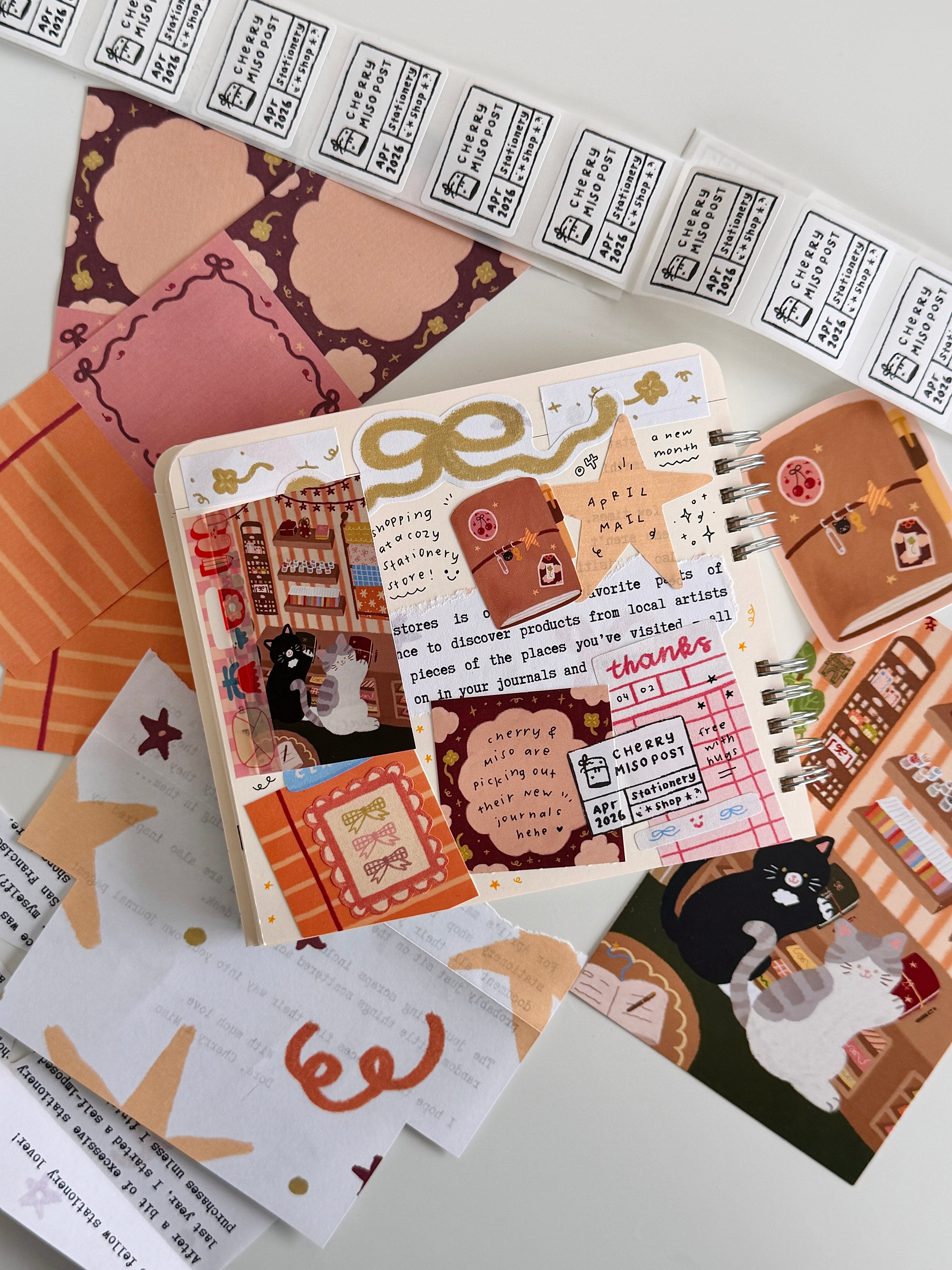Creative flat lay featuring a planner spread with handwritten notes, stickers, and decorative paper elements from the April edition of Cherry Miso Post showcasing unique and cute stationery shop designs.