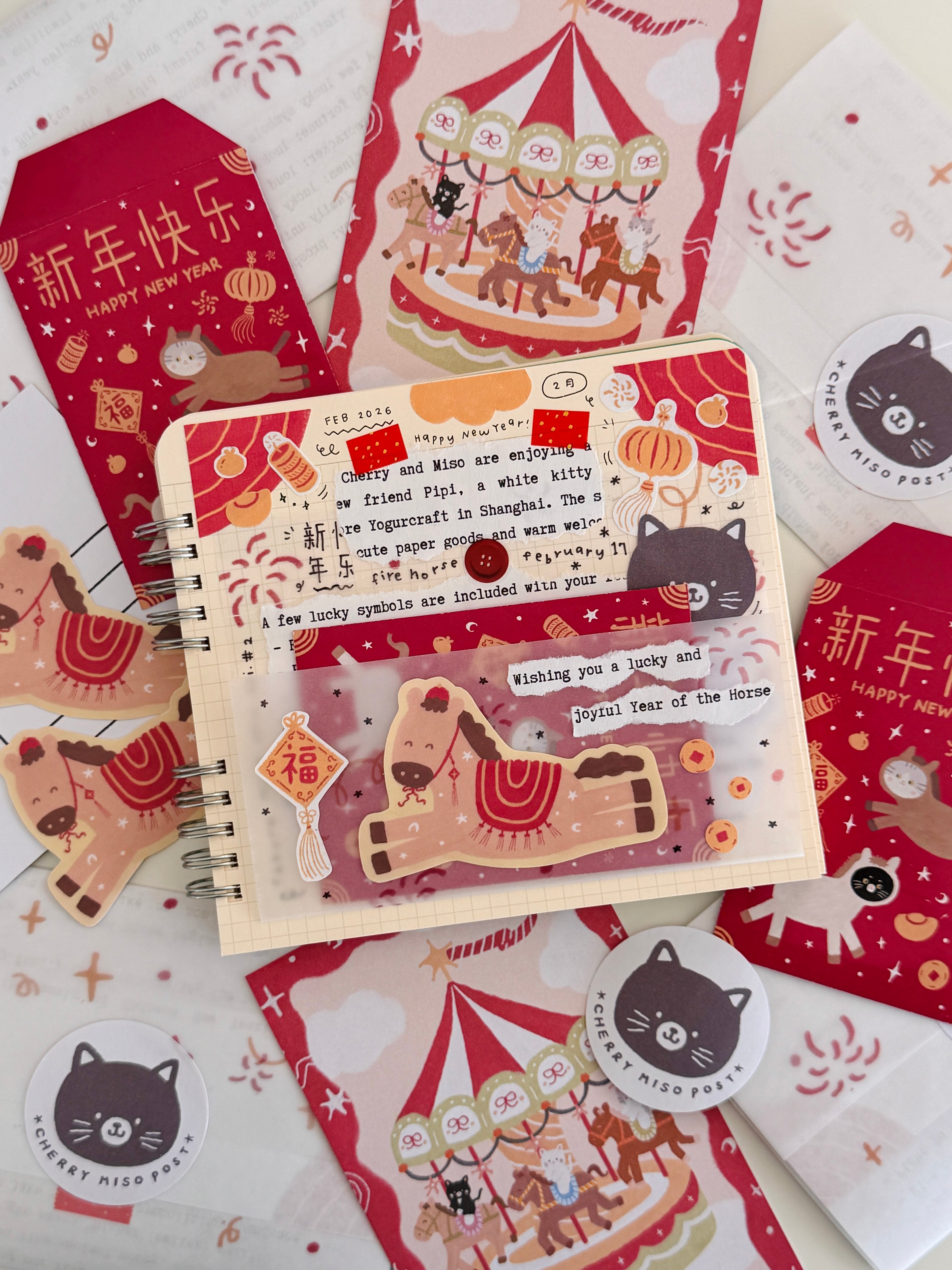Flat lay of colorful stationery items featuring playful cat illustrations, a carousel design, and a journaling page with a horse sticker, part of the February edition of Cherry Miso Post.