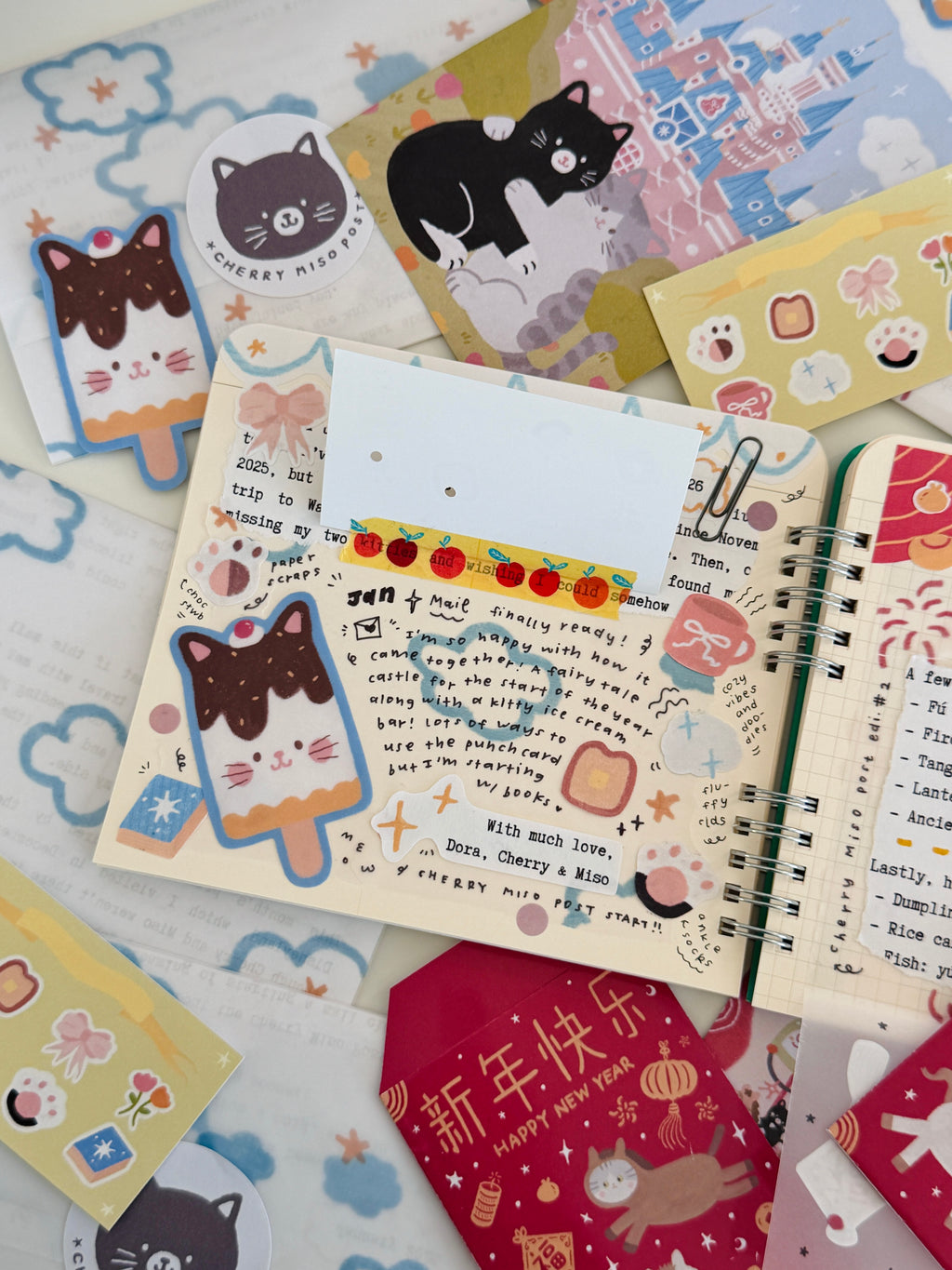 Flat lay of colorful paper stationery featuring cat-themed postcards, stickers, and decorated letters from the January edition of Cherry Miso Post with unique and cute artwork designs.
