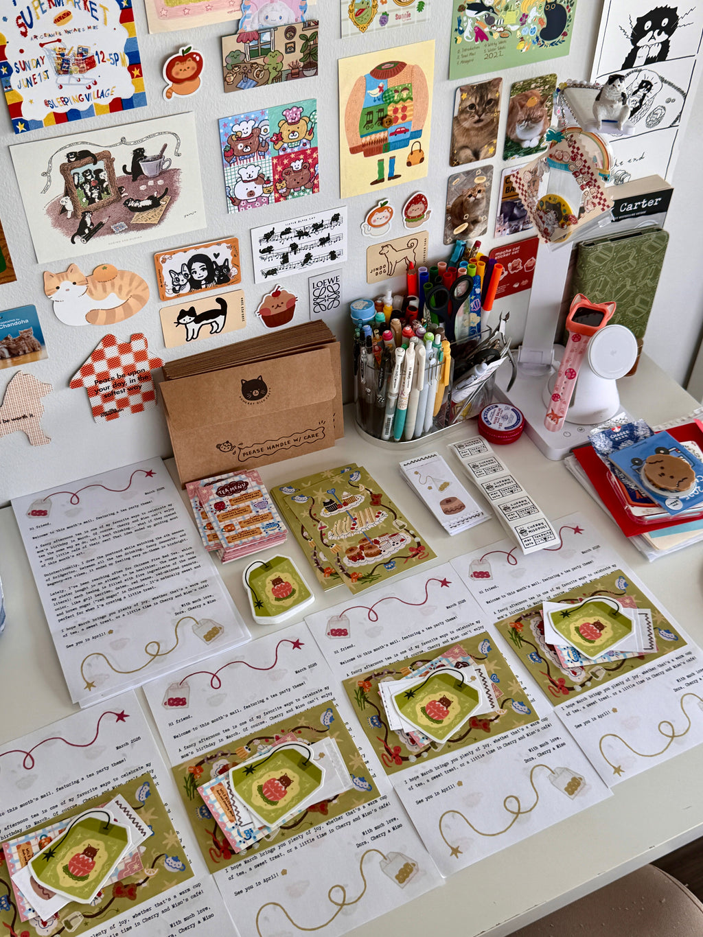 Neatly arranged stacks of stationery items including decorated letters, postcards, envelopes, and stickers from the March edition of Cherry Miso Post, displayed on a desk ready to be packed.