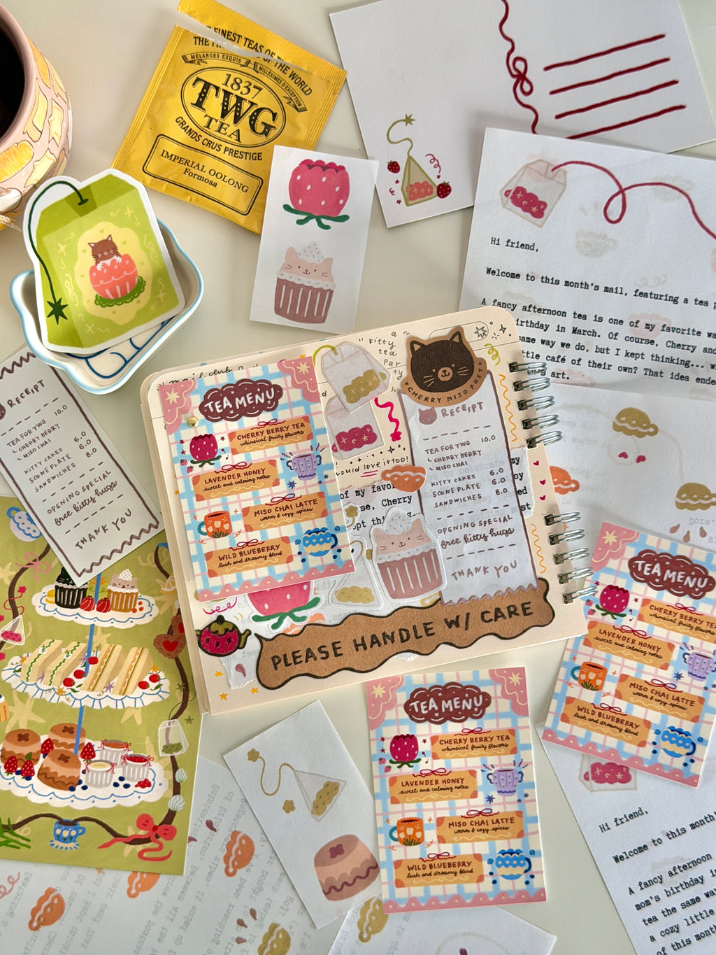 Flat lay of a journal spread featuring colorful stationery, postcards, stickers, and handwritten notes with tea-themed illustrations and cute artwork designs from the March edition of Cherry Miso Post.