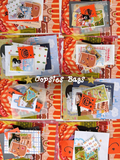 A flatlay of piles of cat-themed stationery items, including postcards, stickers, paper scraps, washi tape, and mini stamps