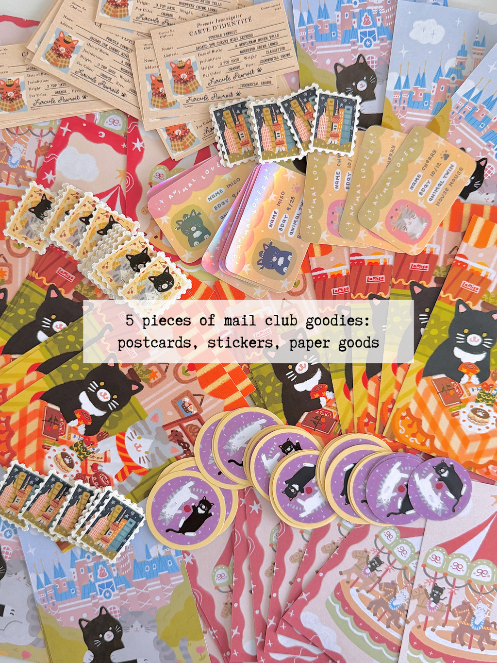 A flatlay of piles of cat-themed stationery items, including postcards, stickers, paper scraps, washi tape, and stamp stickers